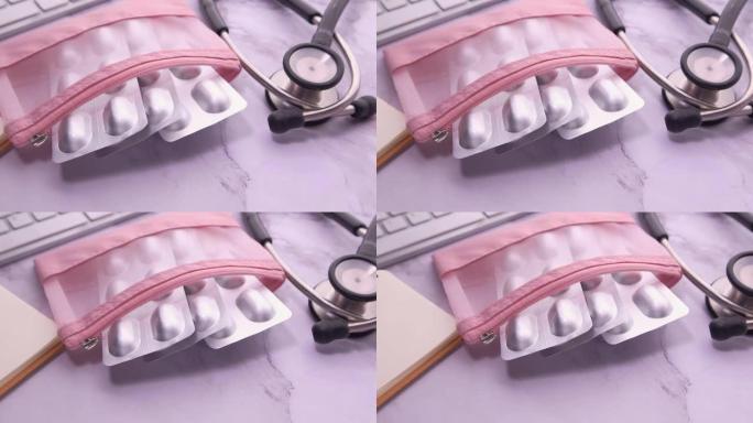 粉色背景上的泡罩包装、听诊器和药盒的俯视图