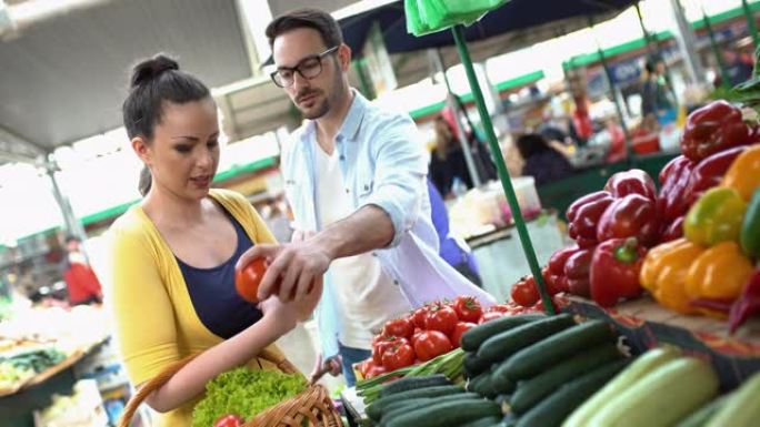 年轻夫妇在农贸市场买蔬菜。