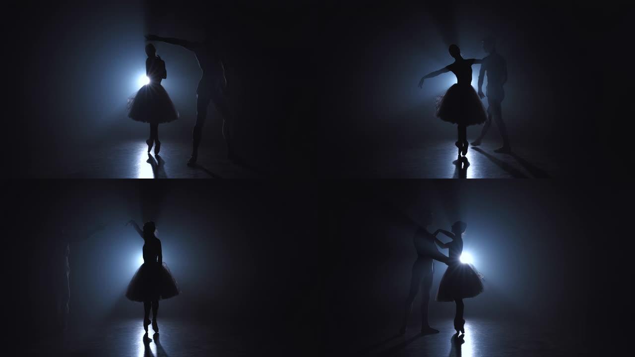 优雅的芭蕾舞演员和她的男搭档在黑暗中用泛光灯背光跳舞古典或现代芭蕾舞的元素。黑色背景上的烟雾情侣。艺