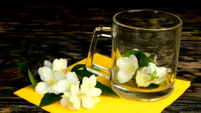 准备茉莉花茶。新鲜的茉莉花花瓣和花朵被扔进玻璃透明茶杯中。
