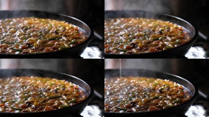 将盐多汁的肉和蔬菜在锅里的酱汁中炖煮，并盖上玻璃透明盖
