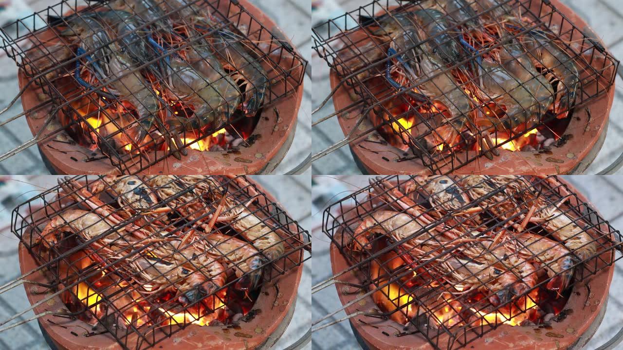 泰国河虾在木炭烤架上烤，在烧烤泰国铁烤架上烤。在泰国街头美食夜市的炭炉上煮巨型烤龙虾。烤巨型河虾。