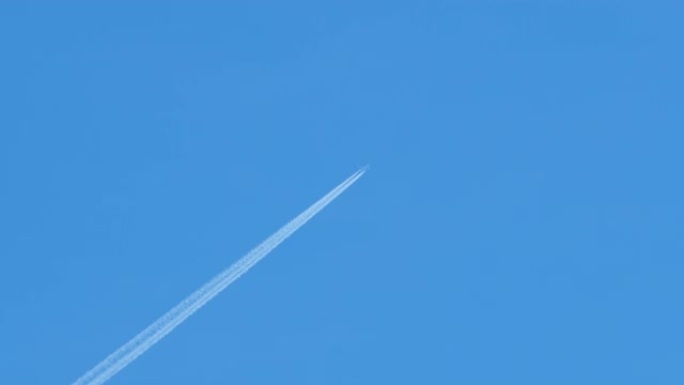 一架在高空飞行的客机留下一条长长的白色涡轮喷气飞机轨迹。