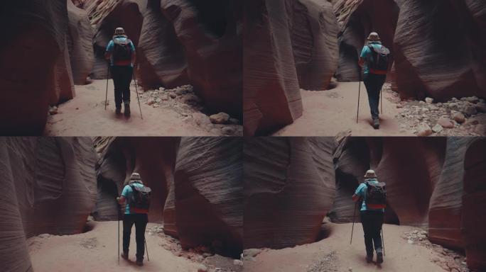 远足者在美国带有橙色光滑岩石的深槽峡谷的河床上徒步旅行