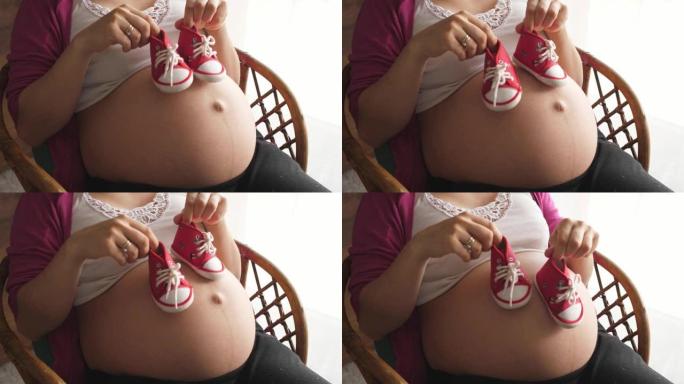 女手玩剧走路走路宝宝小鞋在怀孕的肚子上