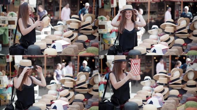 时尚的女孩在当地工艺品市场上试戴巴拿马帽子，看着镜子。市场柜台充满了不同类型和风格的头具，丰富多彩的