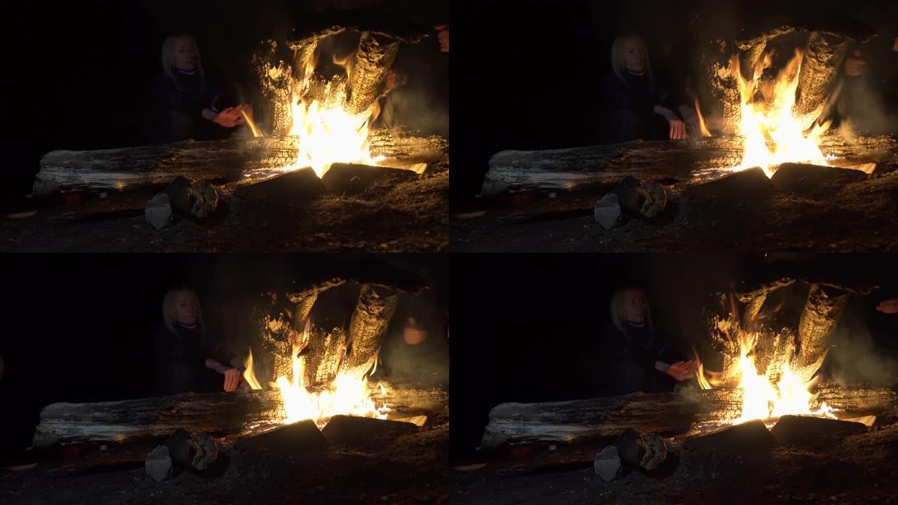 朋友们晚上坐在火炉旁。周围的人篝火，沐浴在火中，放松概念，篝火，放松，希望，人性，自然，游客。