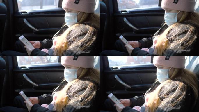 带医用口罩的小女孩乘车旅行并使用手机。乘坐过程中从病毒佩戴防护口罩的女性儿童。冠状病毒大流行带来的安