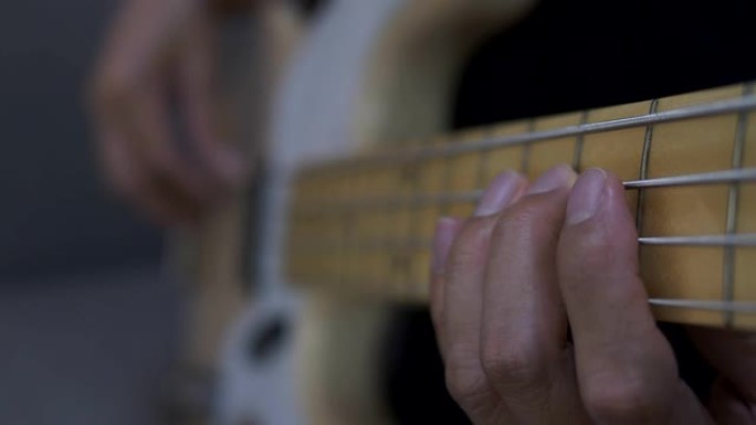 一个男人的手弹奏电吉他贝斯的特写镜头。