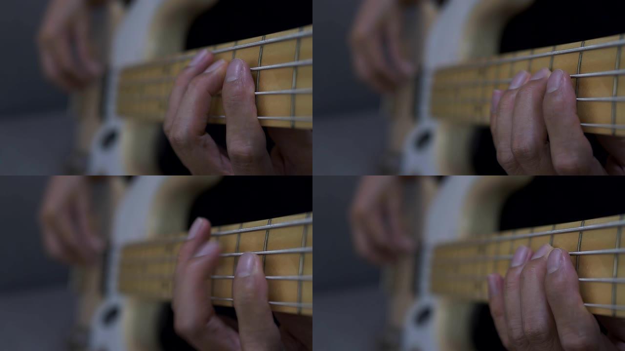 一个男人的手弹奏电吉他贝斯的特写镜头。