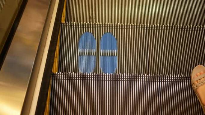 POV，女人脚走在自动扶梯上，地板上的新型冠状病毒肺炎商务标牌，新的正常概念