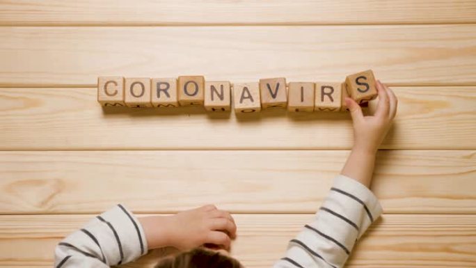 儿童和冠状病毒。COVID-19背景。儿童心理学。孩子们用手列出冠状病毒的单词。流行病、流行病和儿童