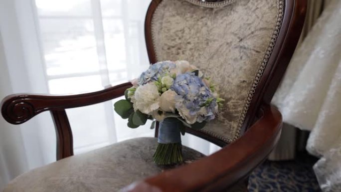 一束白玫瑰和蓝色花朵。椅子上新娘的婚礼花束