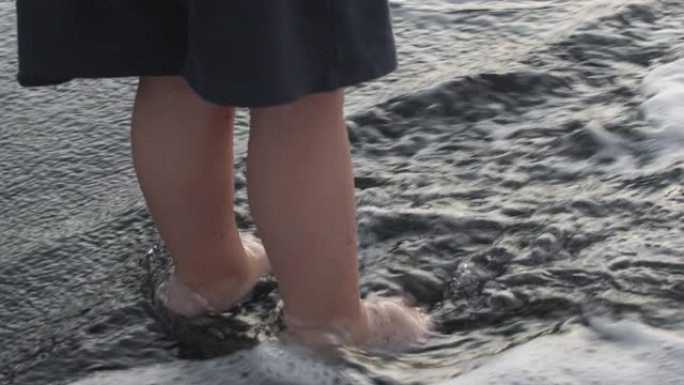 波浪洗孩子的脚的缓慢运动