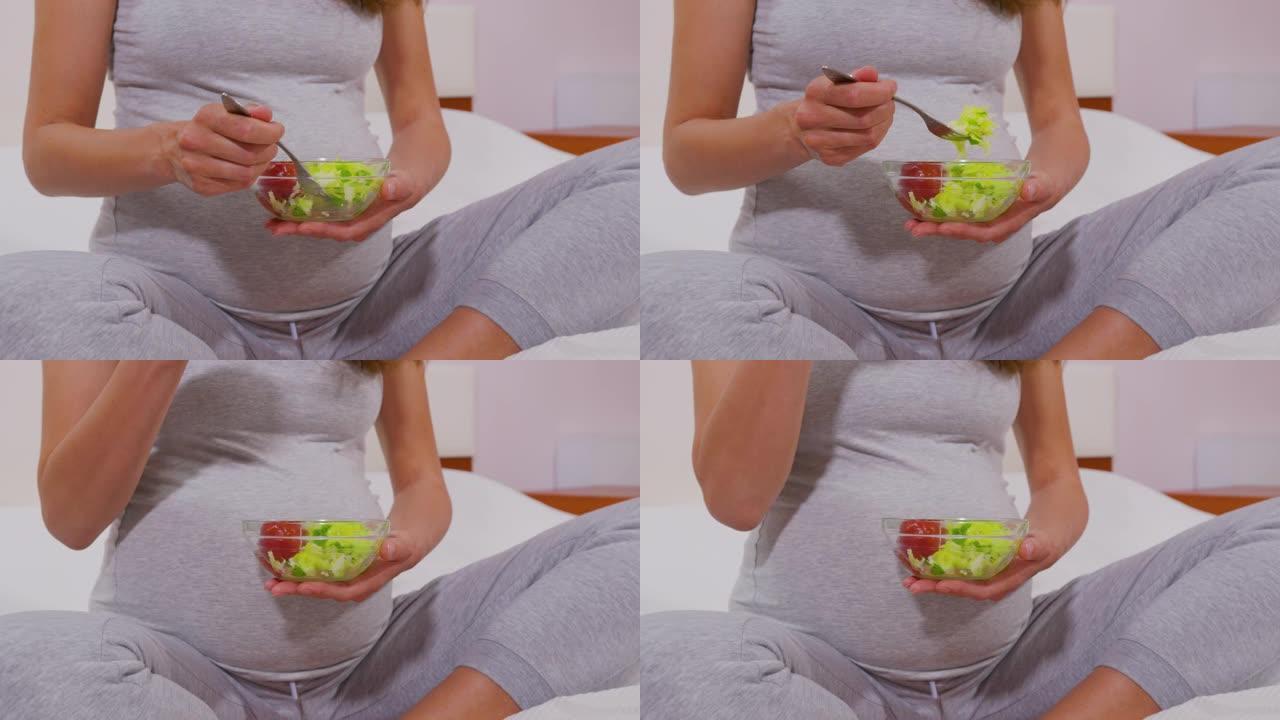 一个孕妇用叉子吃蔬菜沙拉，适当的营养。孕妇吃了对未出生的孩子有用的蔬菜沙拉。正确的营养概念。