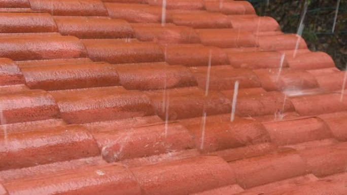 硬雨落在红瓦屋顶的家中并掉落到地面上
