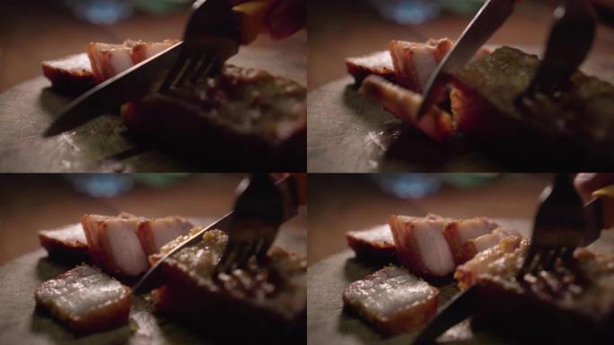 有人在木板上切油炸的脆皮猪肉。通用食品。充满了油。特写镜头。