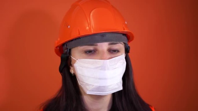 橙色背景上戴着医用面具的年轻女子的肖像。成年女性用口罩遮住脸，以保护自己免受疾病的侵害。冠状病毒流行
