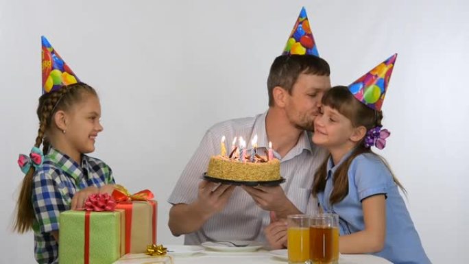 孩子们亲吻坐在节日蛋糕旁的爸爸