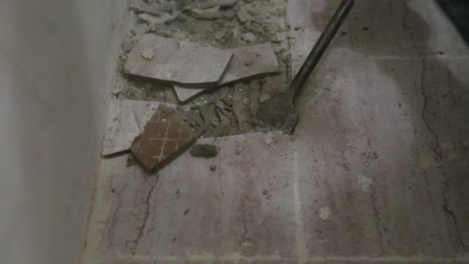 工人从浴室的地板上取下旧瓷砖