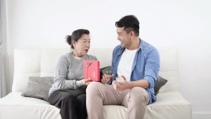 快乐的亚洲男人给母亲送礼盒庆祝母亲节。
