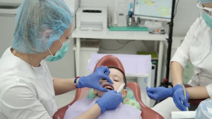 年轻女孩牙医，医生做牙齿检查的孩子。高质量的儿童药品是健康的保证。医生刷他们露齿的病人。现代医疗工具