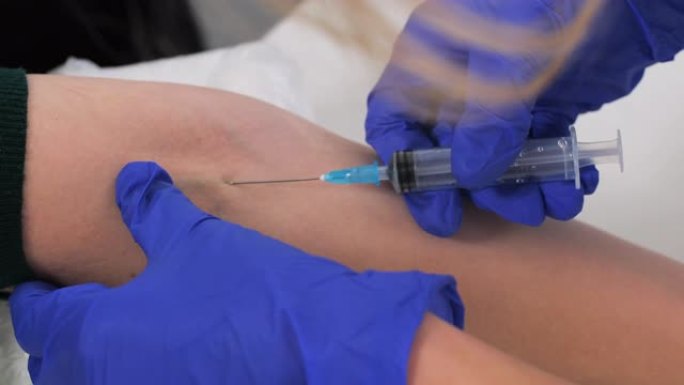 护士手的特写将针插入静脉。一名戴着蓝色防护手套的医务人员将从患者的静脉中采血进行分析。献血，挽救生命