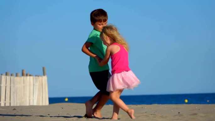 穿着粉红色裙子的小男孩和女孩在海滩上跳舞