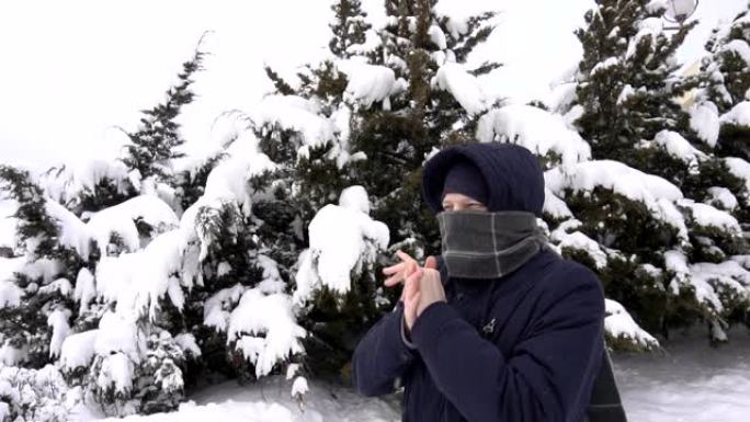 一个穿着围巾的白人年轻人在冬天冻结在大自然上。雪中云杉的树木，慢动作