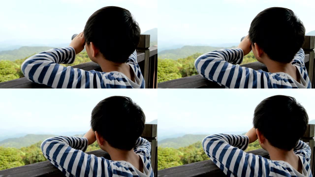 小男孩在亭子上用望远镜看风景