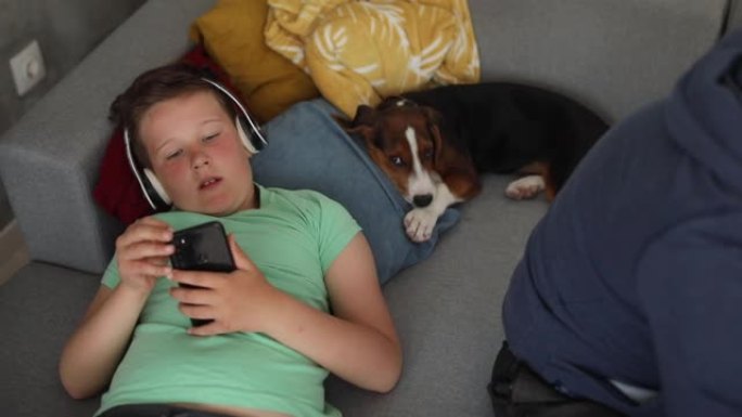 男孩听音乐，在家和狗在沙发上放松