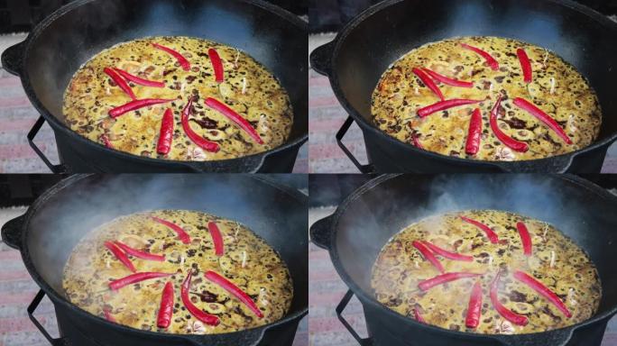 乌兹别克斯坦国家菜抓饭，抓饭，plov，大锅肉米饭。煮沸，在火，红辣椒和整个大蒜的大锅中烹饪过程