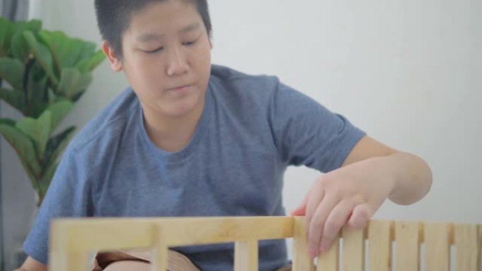 亚洲男孩在家学习如何DIY木制架子。