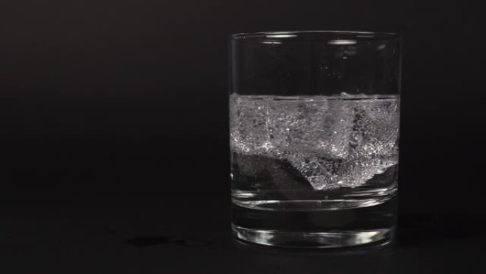 将碳酸透明清水混合在带有冰块的玻璃杯中的特写镜头