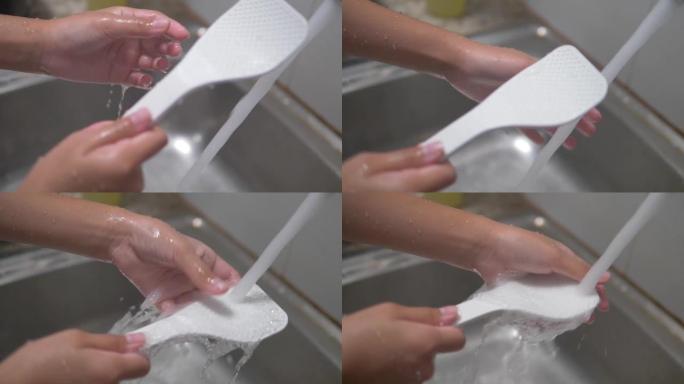 女孩在厨房洗白色塑料钢包，生活方式概念。