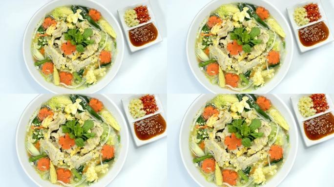 泰国Sukiyaki汤搭配猪肉和蔬菜雕刻胡萝卜花朵形状的酱汁