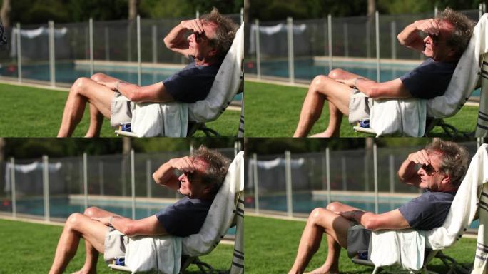 退休的老人从外面晒太阳遮住脸。资深男子休息