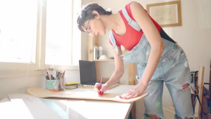 年轻的女艺术家在滑板板上画她的设计理念