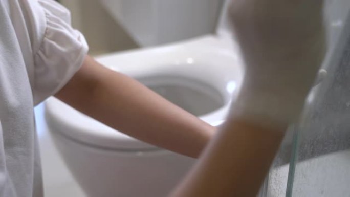 女性手在家里用弹性白手套擦拭浴室玻璃门，玻璃表面材料，消毒湿巾，防止冠状病毒covid19，家庭清洁
