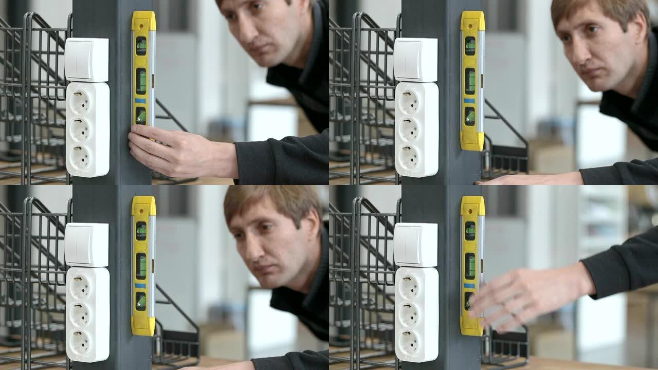 一个人使用黄色水平测量金属柱垂直位置的偏差。