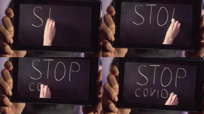 年轻女子的特写显示平板电脑的屏幕，女性的手用粉笔在黑板上写下呼唤停止冠状病毒传播的话语
