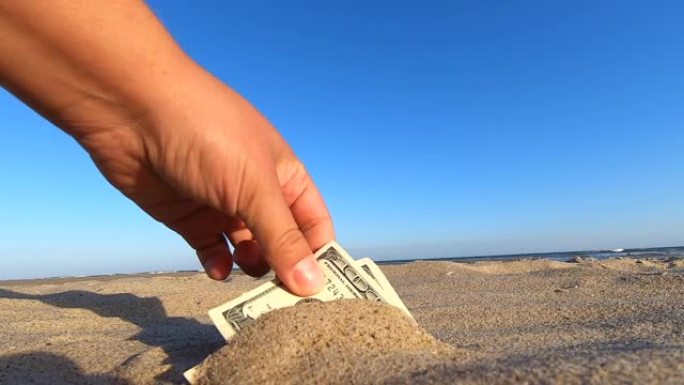 一个女孩从沙子里拿出了300美元的钞票。