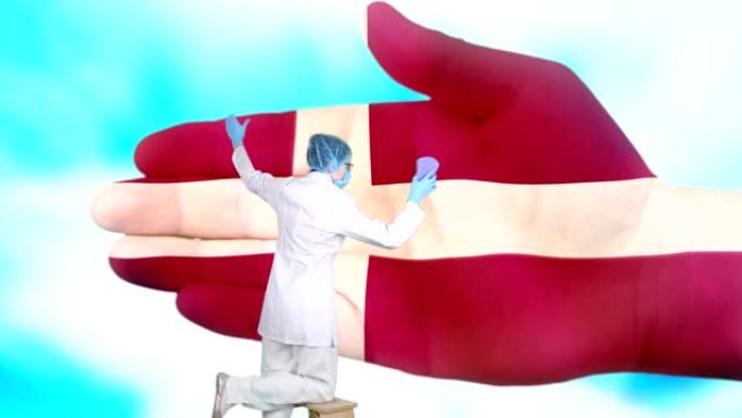 戴着医用口罩和手套的护士洗大手，涂上丹麦国旗的颜色。国家保健。洗手概念。病毒保护。疾病预防