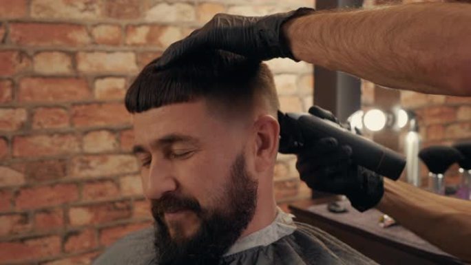 理发店给微笑的男顾客剪发的剪发照片。