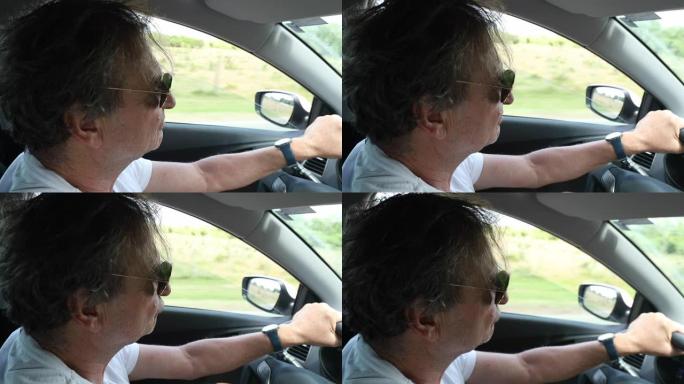 在乡间小路上开车的老人。享受驾驶方向盘的退休老人