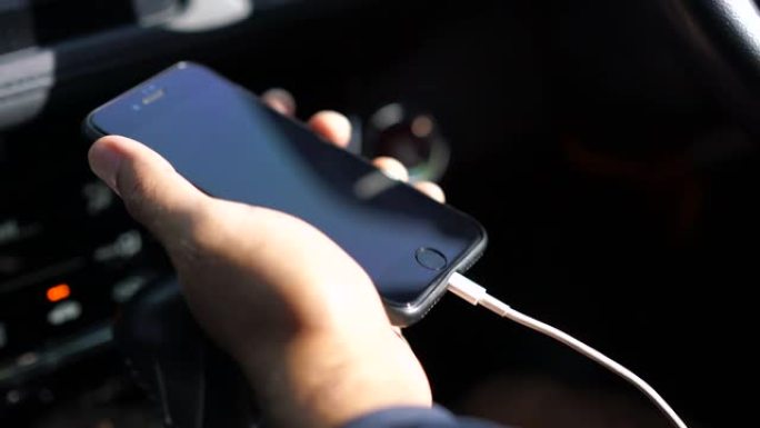 特写男性手握手机在车里充电。4k分辨率。