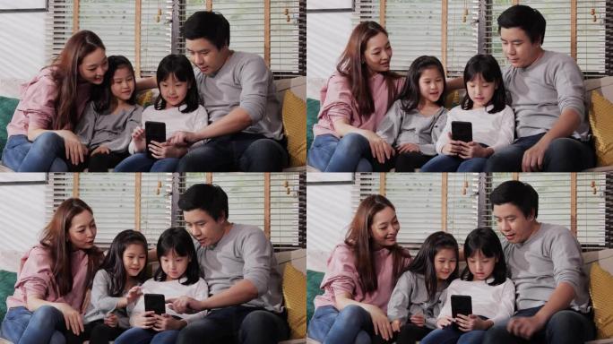 小女孩和她的父母希望在客厅里一起移动。快乐的亚洲家庭笑着一起看智能手机屏幕享受网上购物。