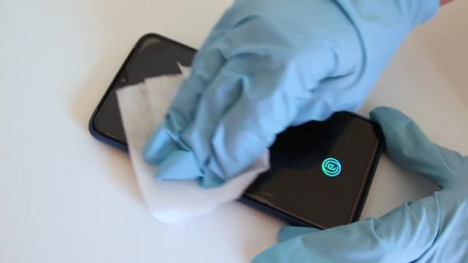 医用乳胶手套中的人用抗菌擦拭清洁智能手机的屏幕，以防止冠状病毒，Covid 19病毒，细菌和桌子上的