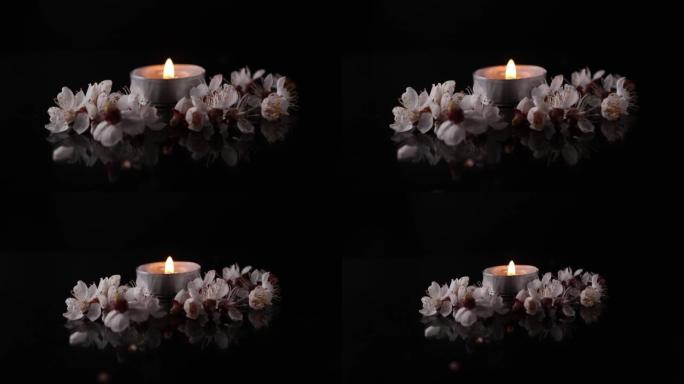黑色背景上鲜花环绕的燃烧蜡烛