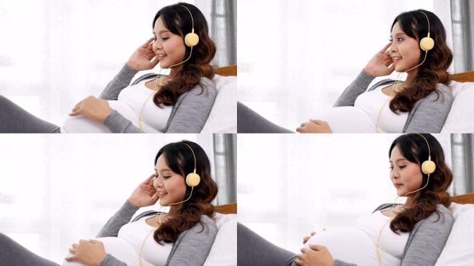 倾斜快乐的亚洲孕妇坐在家里卧室的床上听音乐，怀孕，人和产妇的概念，慢动作